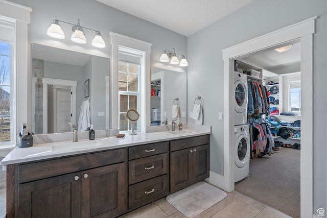full bathroom featuring stacked washing machine and dryer, double vanity, a spacious closet, and tile patterned floors