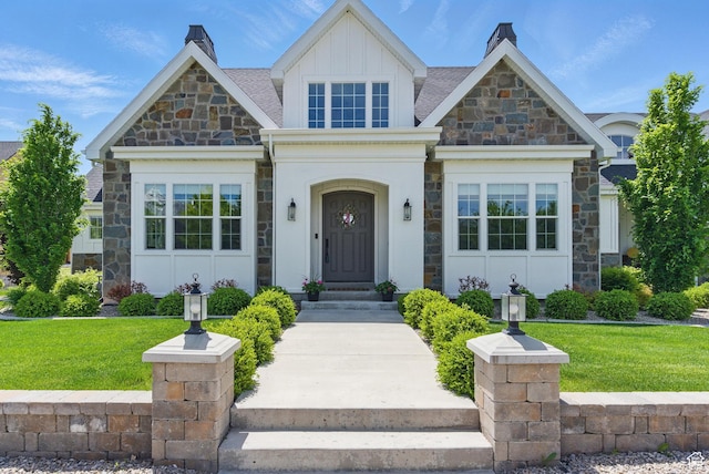 view of front of property with stone siding, a front yard, and board and batten siding