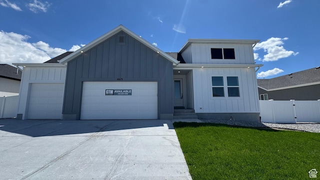 modern farmhouse featuring fence, a garage, board and batten siding, a front yard, and driveway