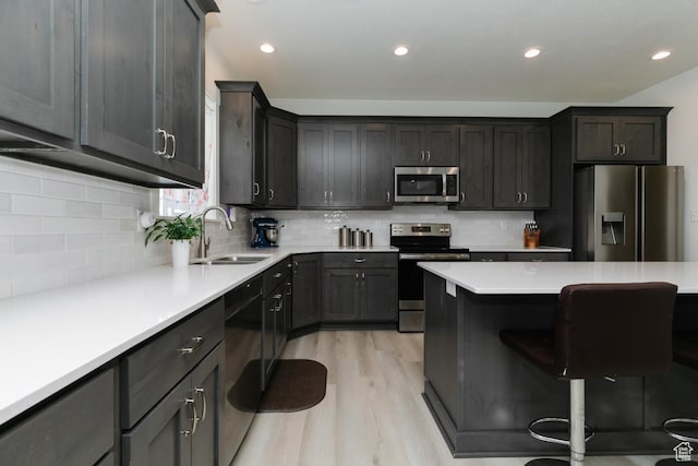 637 S 4th W, Preston, ID 83263 - kitchen featuring appliances with stainless steel finishes, a sink, a kitchen breakfast bar, light wood-style floors, and tasteful backsplash