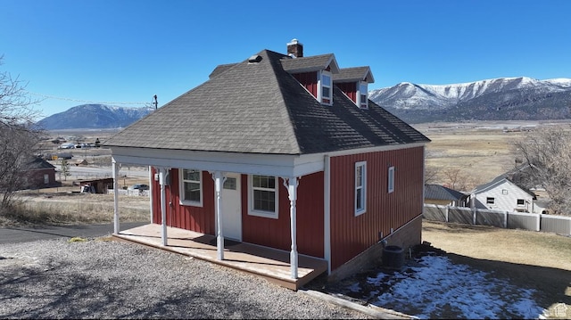 exterior space with fence, a mountain view, and an outbuilding