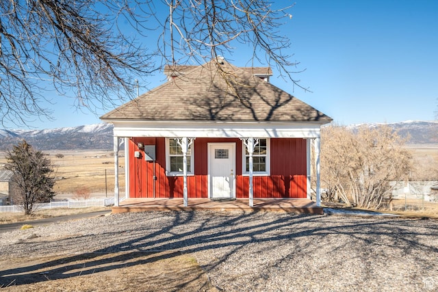 view of front of home with a shingled roof, an outdoor structure, and a mountain view