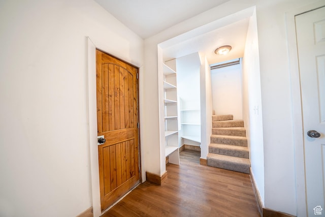 hall featuring baseboards, stairway, and wood finished floors