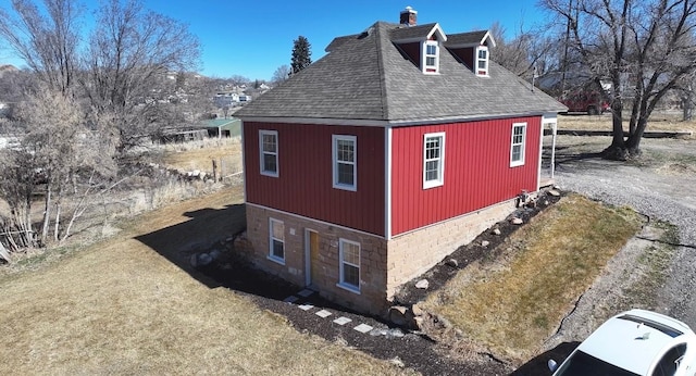 view of side of property featuring a yard, a shingled roof, and a chimney