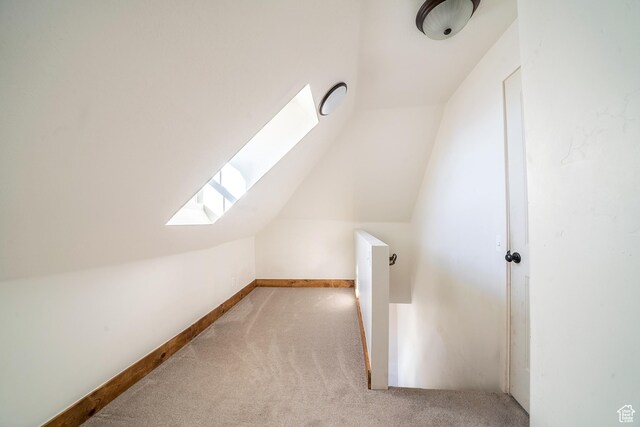 additional living space featuring carpet floors, vaulted ceiling with skylight, and baseboards