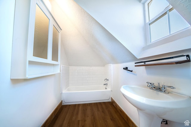 bathroom featuring a sink, baseboards, a bath, and wood finished floors