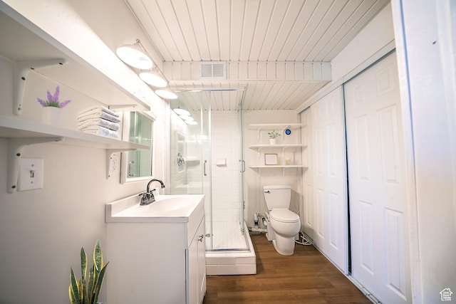 bathroom with visible vents, toilet, wood finished floors, vanity, and a shower stall