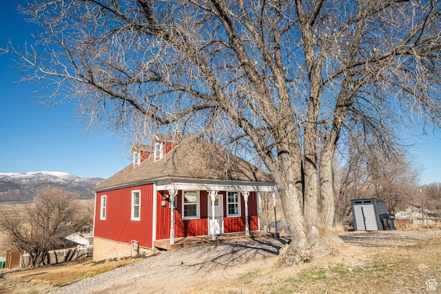 view of front of property featuring an outdoor structure, dirt driveway, and a mountain view