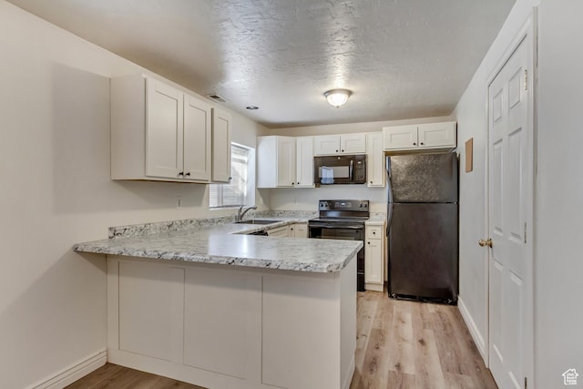 kitchen featuring a peninsula, black appliances, light countertops, and light wood-style floors