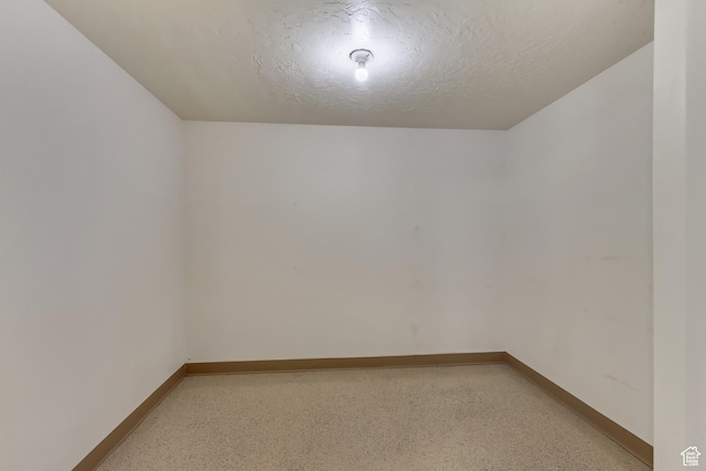 spare room with baseboards, light speckled floor, and a textured ceiling
