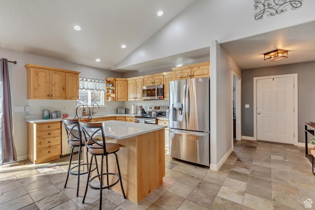 kitchen with light countertops, appliances with stainless steel finishes, light brown cabinets, and a center island