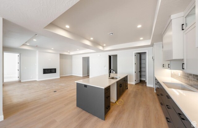 1519 N Horizon Pkwy Unit 98, Washington, UT 84780 - kitchen featuring a tray ceiling, a center island with sink, light countertops, a glass covered fireplace, and recessed lighting