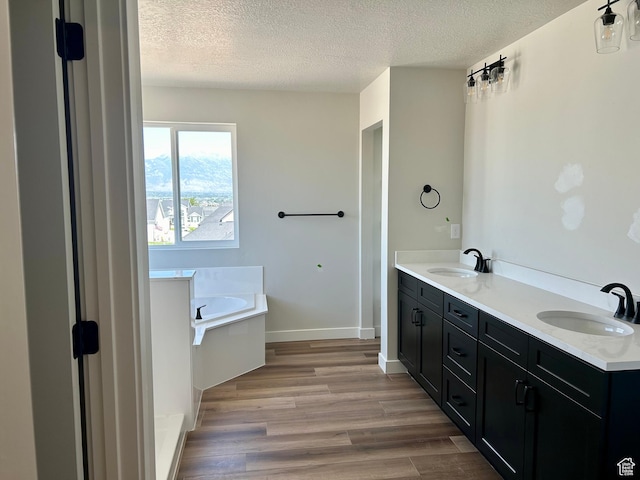 1552 N Cozy Ln Unit 05, Saratoga Springs, UT 84045 - full bathroom featuring a textured ceiling, a bath, wood finished floors, double vanity, and baseboards