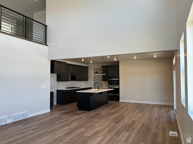 1552 N Cozy Ln Unit 05, Saratoga Springs, UT 84045 - kitchen featuring stainless steel microwave, open floor plan, double wall oven, a high ceiling, and wood finished floors