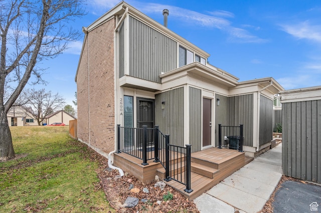 back of property featuring brick siding and a lawn