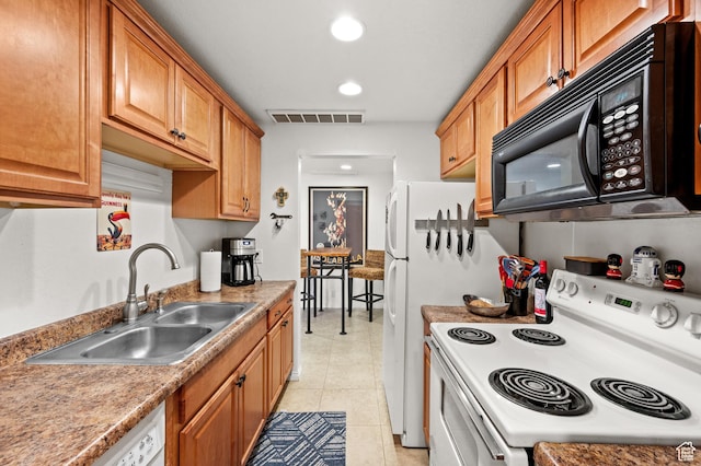 kitchen featuring light tile patterned floors, visible vents, brown cabinetry, a sink, and white appliances