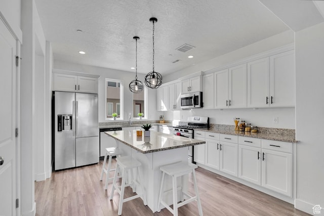 kitchen with light wood finished floors, visible vents, appliances with stainless steel finishes, and a center island