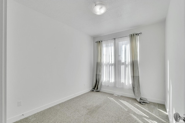 carpeted empty room with baseboards and a textured ceiling