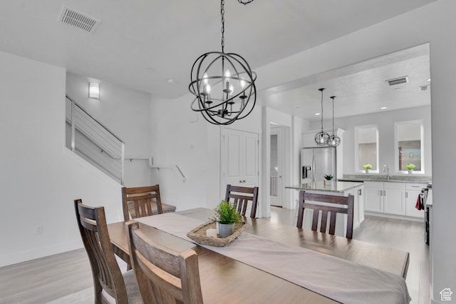 dining area with light wood finished floors, recessed lighting, visible vents, and an inviting chandelier