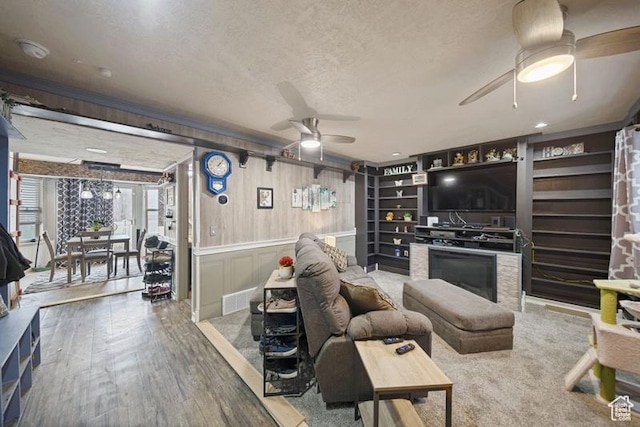 204 W Crescent View Ln N Unit 111, Tooele, UT 84074 - living area featuring a textured ceiling, a fireplace, wood finished floors, visible vents, and a ceiling fan