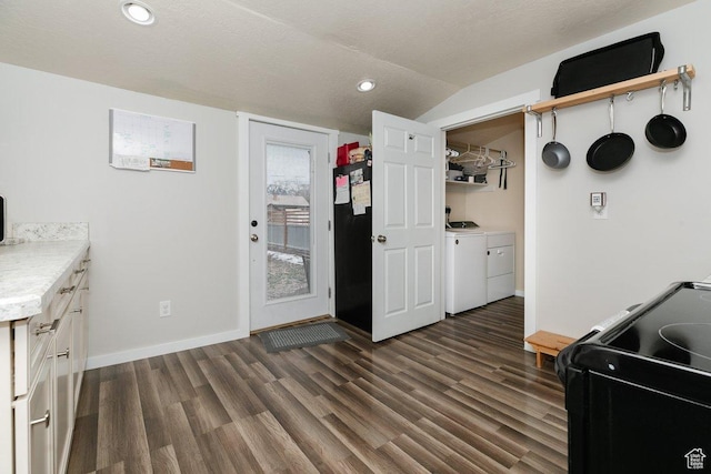kitchen featuring lofted ceiling, dark wood-type flooring, baseboards, and washer and dryer