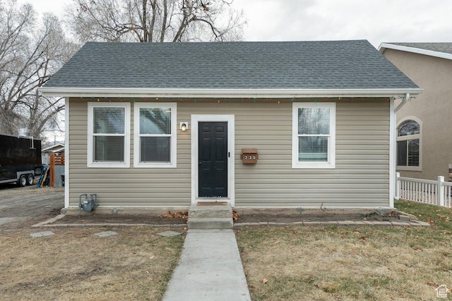 bungalow-style house with a shingled roof and fence