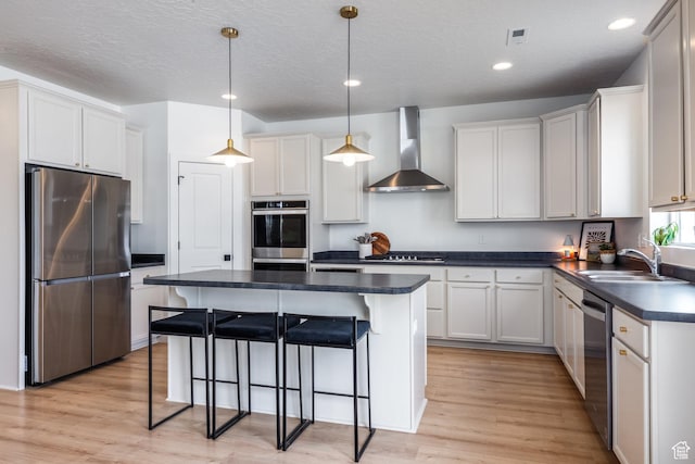4623 N Festival Way, Eagle Mountain, UT 84005 - kitchen with light wood finished floors, stainless steel appliances, dark countertops, wall chimney range hood, and a sink