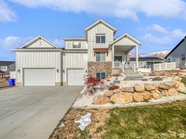 view of front of house with driveway, stone siding, board and batten siding, and an attached garage