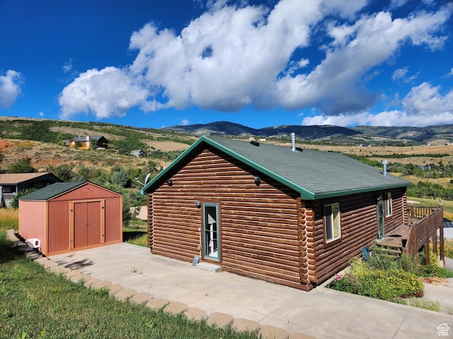 1538 N Mackinaw Way, Garden City, UT 84028 - view of side of property featuring a shingled roof, log siding, an outbuilding, a shed, and a mountain view