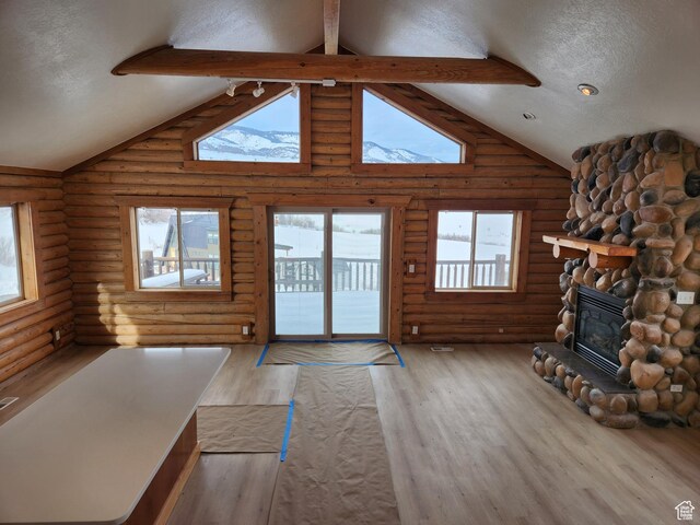 1538 N Mackinaw Way, Garden City, UT 84028 - unfurnished living room with a textured ceiling, high vaulted ceiling, a stone fireplace, wood finished floors, and beam ceiling