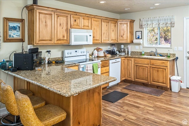 275 W 60 S, Hyde Park, UT 84318 - kitchen featuring a sink, wood finished floors, white appliances, a peninsula, and a kitchen bar