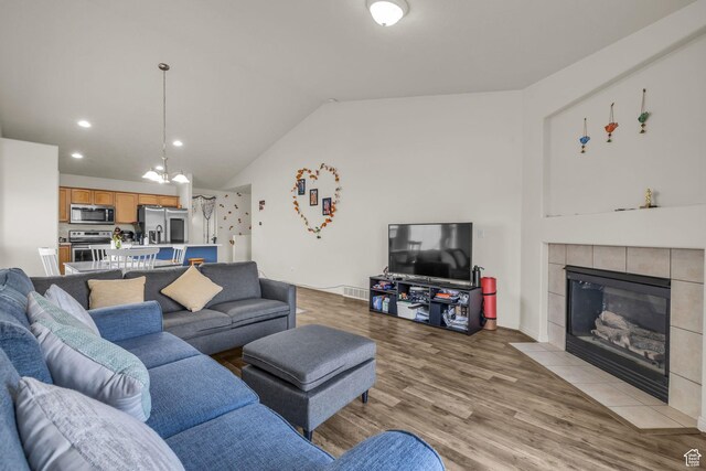 8282 S 6430 W, West Jordan, UT 84081 - living area featuring light wood finished floors, a tile fireplace, lofted ceiling, a chandelier, and recessed lighting