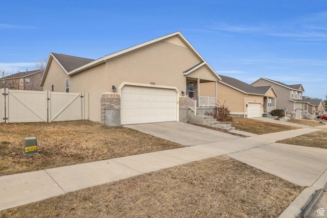 8282 S 6430 W, West Jordan, UT 84081 - view of front of home with stucco siding, concrete driveway, a gate, a garage, and a residential view