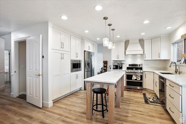 1434 Bennett Cir, Farmington, UT 84025 - kitchen with light wood-style flooring, a sink, white cabinets, appliances with stainless steel finishes, and custom range hood