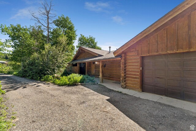 1973 W Modoc Loop, Coalville, UT 84017 - view of front of house featuring a garage, log exterior, and roof with shingles