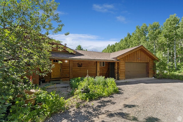 1973 W Modoc Loop, Coalville, UT 84017 - view of front facade with log siding, an attached garage, and a shingled roof