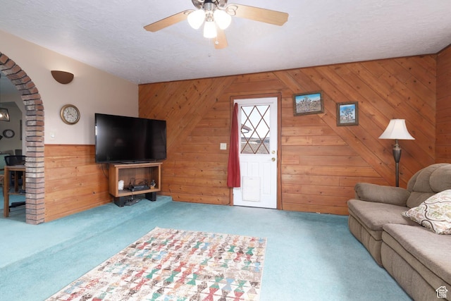 86 E 1000 S, Panguitch, UT 84759 - unfurnished living room featuring arched walkways, a textured ceiling, wooden walls, carpet flooring, and a ceiling fan