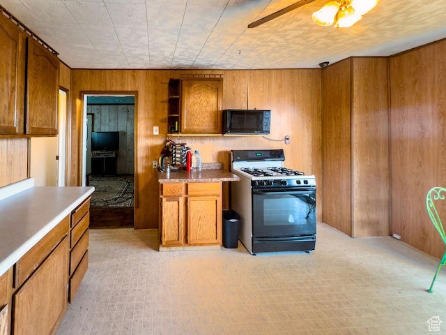 138 W 100 N, East Carbon, UT 84520 - kitchen with black appliances, wooden walls, brown cabinetry, ceiling fan, and open shelves