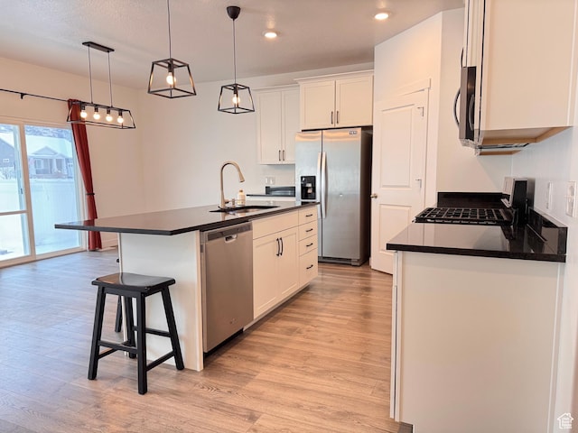 kitchen featuring a sink, dark countertops, light wood finished floors, and stainless steel appliances