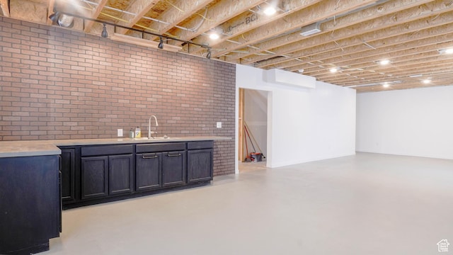 interior space featuring a sink, indoor wet bar, concrete floors, and brick wall