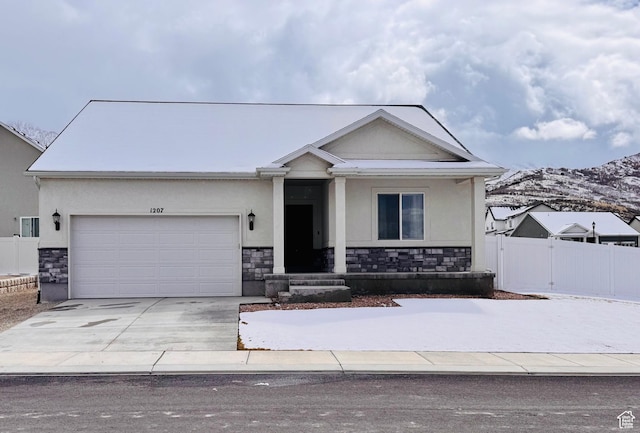 view of front of property featuring stucco siding, stone siding, fence, concrete driveway, and a garage