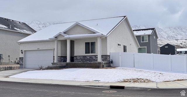 view of front of property featuring fence, a porch, stucco siding, a garage, and stone siding