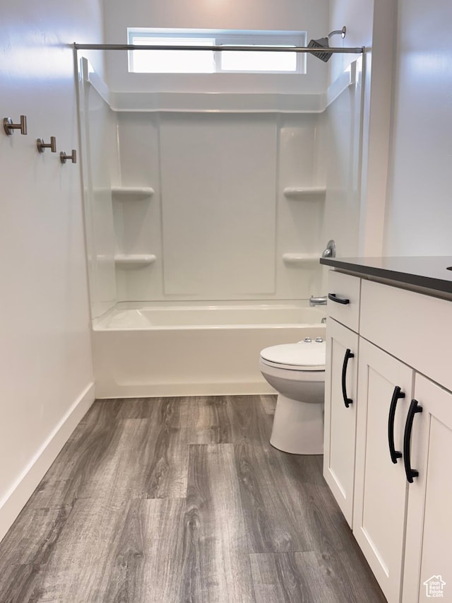 bathroom with vanity, wood finished floors, baseboards, bathtub / shower combination, and toilet