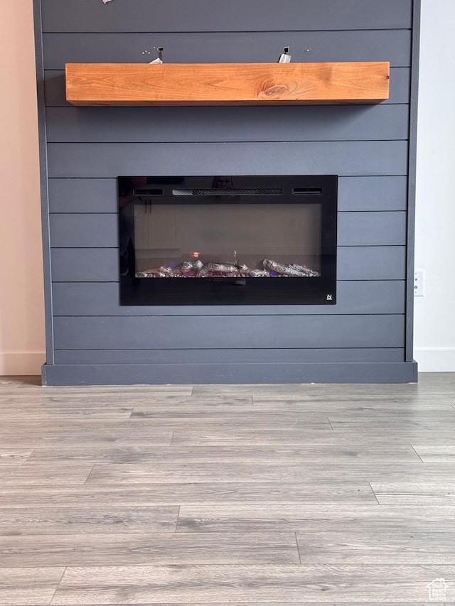 details featuring a large fireplace, baseboards, and wood finished floors