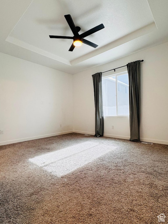 unfurnished room with a raised ceiling, light colored carpet, and baseboards