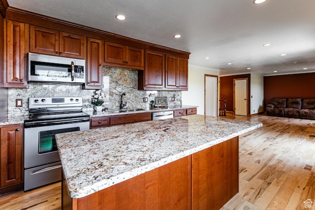 kitchen with stainless steel appliances, light wood-style floors, a sink, and backsplash