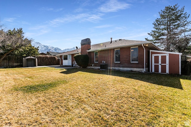 rear view of house featuring central AC, a shed, fence, and brick siding