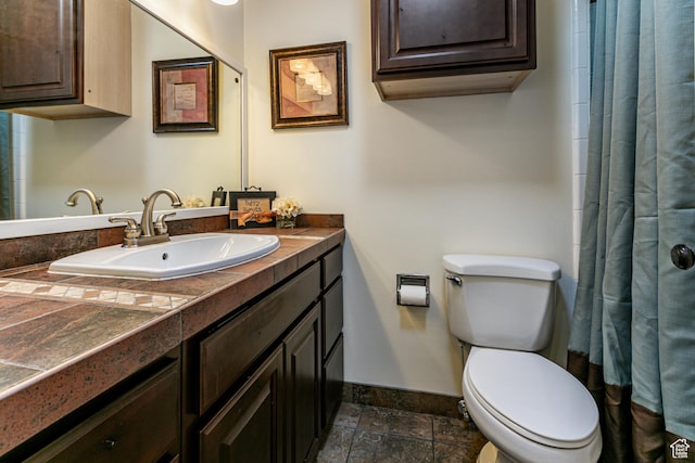 full bathroom with toilet, a shower with shower curtain, vanity, baseboards, and stone finish floor