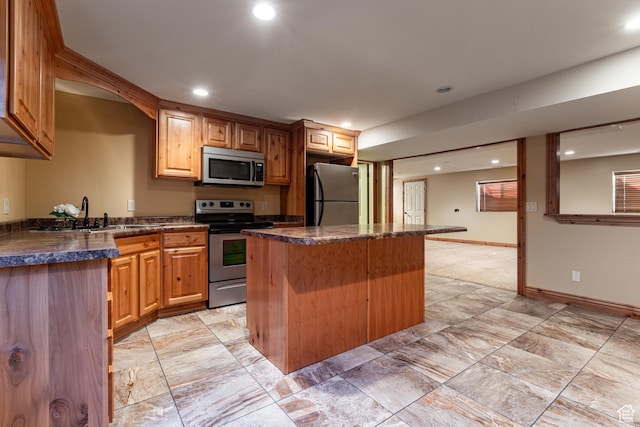 kitchen featuring recessed lighting, a sink, appliances with stainless steel finishes, a center island, and dark countertops