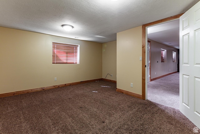 empty room with carpet flooring, a textured ceiling, and baseboards